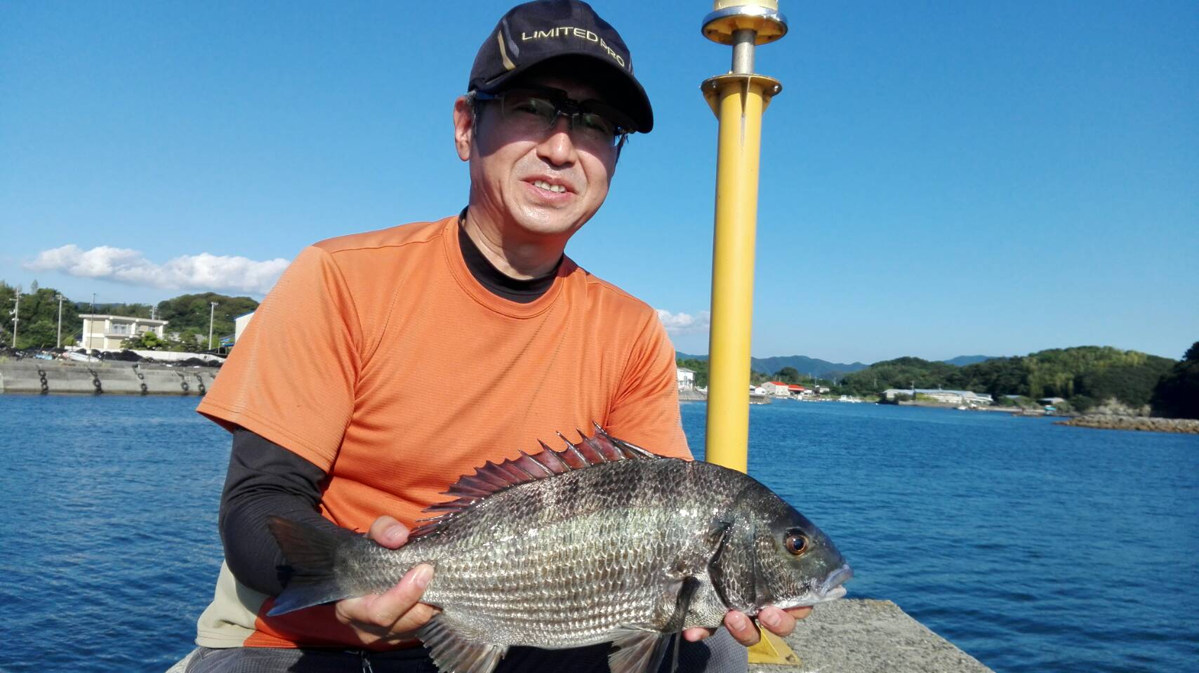 船上で釣った魚を手にする松本さん